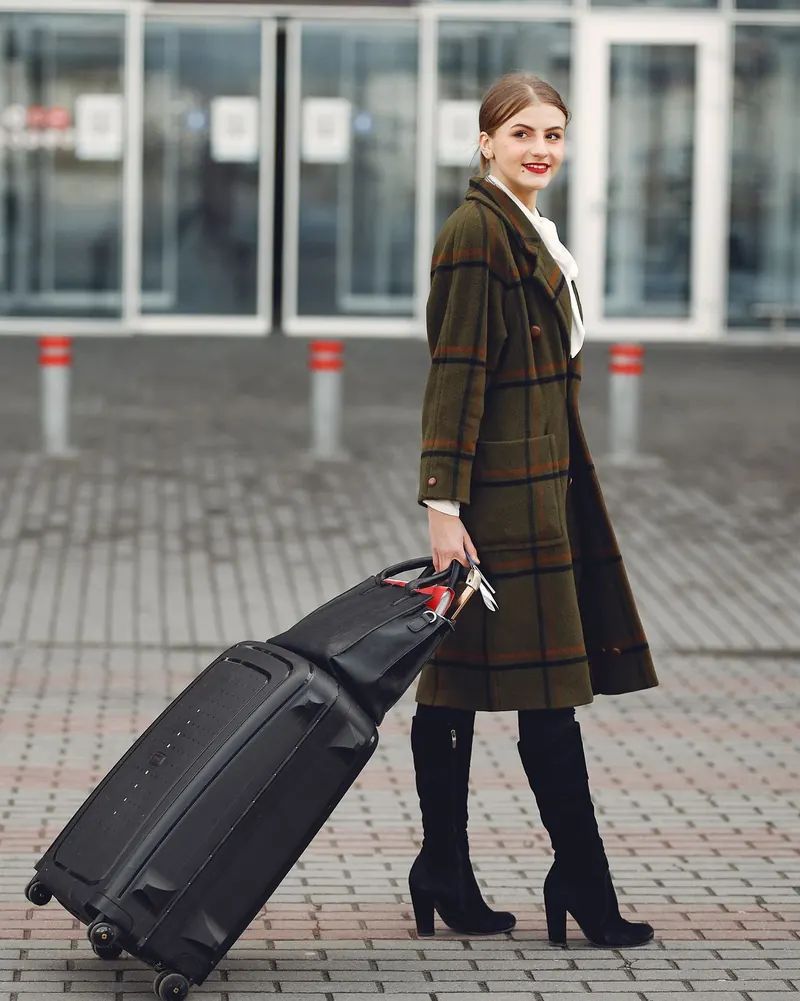 Reisende mit Rollkoffer vor einem Flughafenterminal