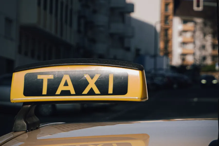 Gelbes Taxischild auf dem Dach eines Taxis in der Stadt